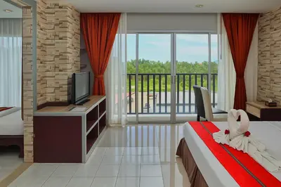 a bedroom with a bed and a tv and a balcony at Bellevue Ocean Patong in Patong Beach