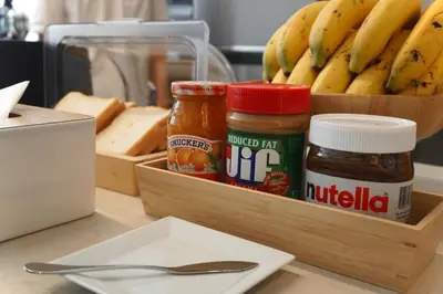 a wooden tray with peanut butter and jelly and a box of bread and bananas at Kuha Phuket Old Town in Phuket Town
