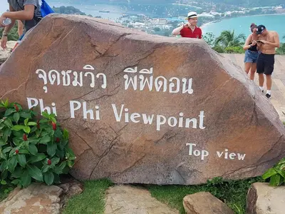 people standing next to a rock with a sign on it at PP Insula in Phi Phi Don