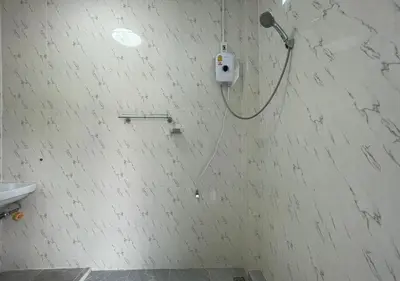 a white tiled bathroom with a shower head on the wall at Amazing Seaview 2-Bedroom House in Patong in Patong Beach
