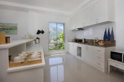 a white kitchen with white cabinets and a window at Oceanview Kata Penthouse - Pasifora in Kata Beach