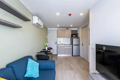 a living room with a blue couch and a kitchen at Classic Studio Apt T3-329 in Chalong