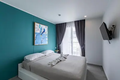 a bedroom with a bed with a blue wall at Pool View 1 Bed Apt T2-620 in Chalong