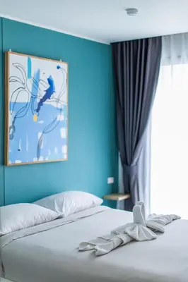 a bedroom with a bed with a blue wall at Pool View 1 Bed Apt T2-620 in Chalong
