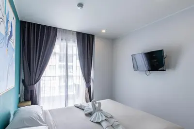 a bedroom with a bed with a window and a television at Pool View 1 Bed Apt T2-620 in Chalong