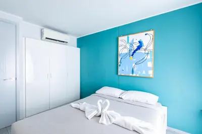 a bedroom with a blue wall and a white bed at Pool View 1 Bed Apt T2-620 in Chalong