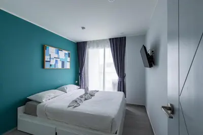 a bedroom with a bed with a blue wall at Pool View 1 Bed Apt T2-720 in Chalong