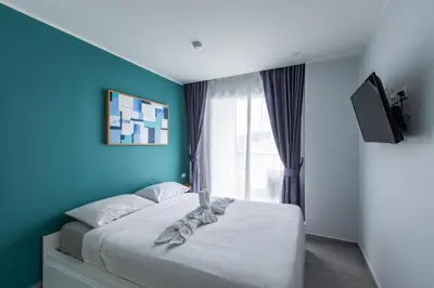 a bedroom with a bed with blue walls and a window at Pool View 1 Bed Apt T2-720 in Chalong