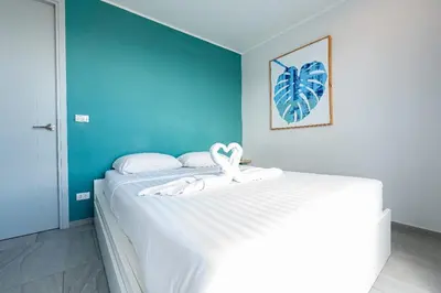 a bedroom with a white bed with a blue wall at Sleek 2 Bed Apt T2-818 in Chalong