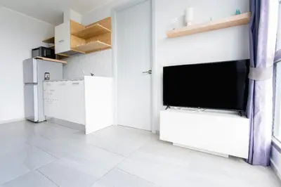 a living room with a tv and a white wall at Sleek 2 Bed Apt T2-818 in Chalong