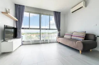 a living room with a couch and a television at Sleek 2 Bed Apt T2-818 in Chalong