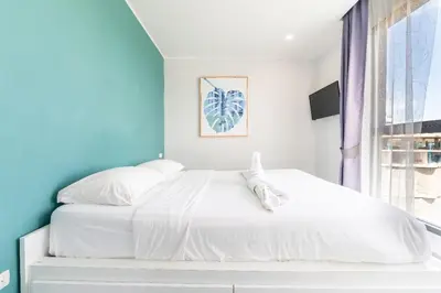 a bedroom with a white bed and a blue wall at Sleek 2 Bed Apt T2-818 in Chalong