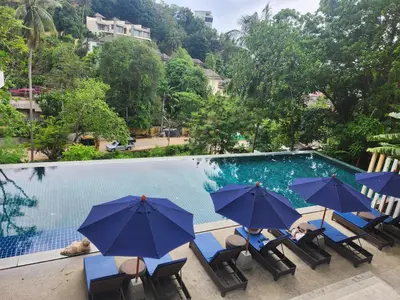a group of chairs with umbrellas next to a swimming pool at veloche group 2 in Karon Beach