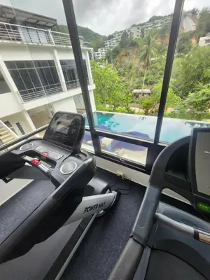 a gym with a view of a swimming pool at veloche group 2 in Karon Beach