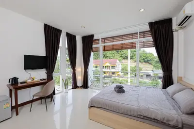a bedroom with a bed and a desk and a window at StayKa Suites in Karon Beach