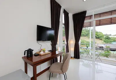 a room with a desk with a television and a chair at StayKa Suites in Karon Beach