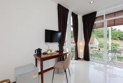 a room with a desk with a television and a window at StayKa Suites in Karon Beach