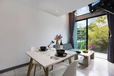 a dining room with a table and chairs and a window at Duplex in NaiHarn Residence near the Beach, UTL B325 in Rawai Beach