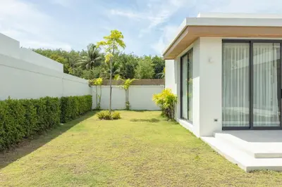 a white house with a fence and a yard at Mouana Breeze Maikhao VIP 4-bedroom Pool Villa 9915 in Mai Khao Beach