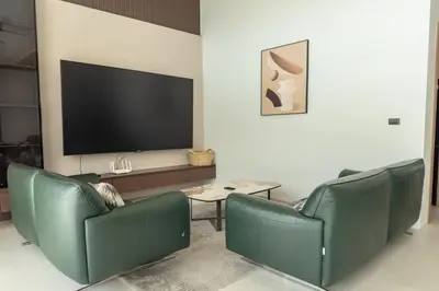 a living room with two green chairs and a flat screen tv at Mouana Breeze Maikhao VIP 4-bedroom Pool Villa 9915 in Mai Khao Beach