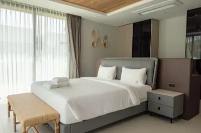 a bedroom with a large white bed with a chair at Mouana Breeze Maikhao VIP 4-bedroom Pool Villa 9915 in Mai Khao Beach