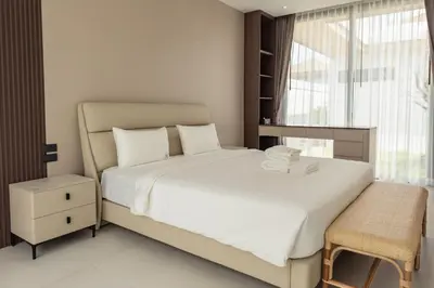 a bedroom with a white bed with a chair and a window at Mouana Breeze Maikhao VIP 4-bedroom Pool Villa 9915 in Mai Khao Beach