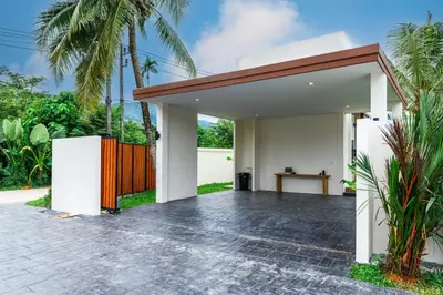 a white house with a wooden fence and palm trees at Dutch Villas Phuket in Koh Lone