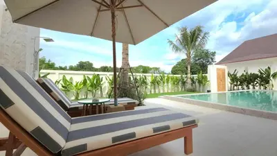 a chair with an umbrella next to a swimming pool at Dutch Villas Phuket in Koh Lone