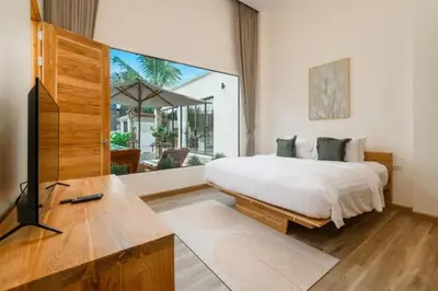 a bedroom with a bed and a tv and a window at Dutch Villas Phuket in Koh Lone