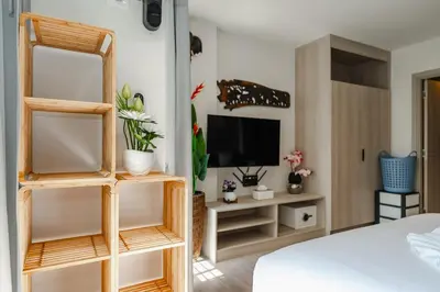 a room with a bed and a tv and shelves at C175 Stylish Condo with Pool View D Condo Phuket in Kathu