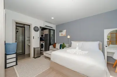 a bedroom with a white bed and a living room at C175 Stylish Condo with Pool View D Condo Phuket in Kathu
