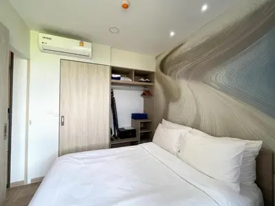 a bedroom with a white bed with a wave wall at Apartment at Skypark Laguna next to golf course in Bang Tao Beach