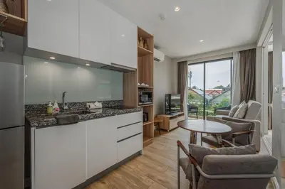 a kitchen with white cabinets and a table with chairs at C176 Diamond Paradise Getaway Condo Phuket in Bang Tao Beach