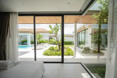 a bedroom with a view of a pool from a house at Mouana Breeze Maikhao VIP 4-bedroom Pool Villa 9916 in Mai Khao Beach