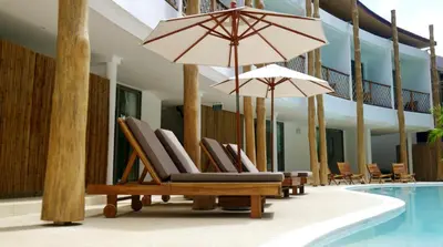a group of chairs and umbrellas next to a swimming pool at The TALAY in Ban Na Tai