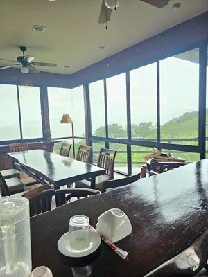 a dining room with tables and chairs and a large window at The house on the hill in Ban Na Kok