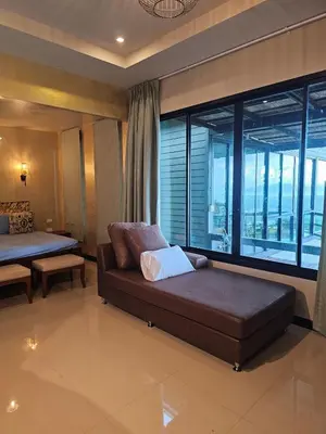 a living room with a couch and a large window at The house on the hill in Ban Na Kok
