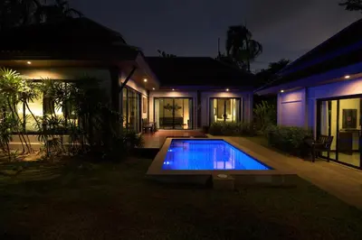 a house with a swimming pool at night at Green Garden Villa Hotel in Nai Harn Beach