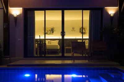 a house with a swimming pool at night with a bedroom at Green Garden Villa Hotel in Nai Harn Beach