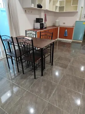 a kitchen with a wooden table and chairs on a tile floor at Maison local avec terrasse et cuisine extérieure Proche Patong in Kathu