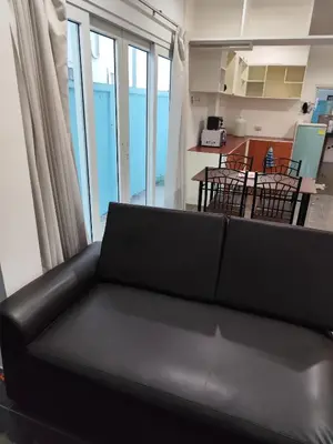 a black couch in a living room with a table and chairs at Maison local avec terrasse et cuisine extérieure Proche Patong in Kathu