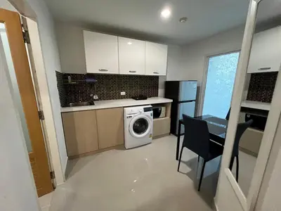 a kitchen with a washing machine and a table and chairs at Plus 1 Condo 202-67 in Kathu