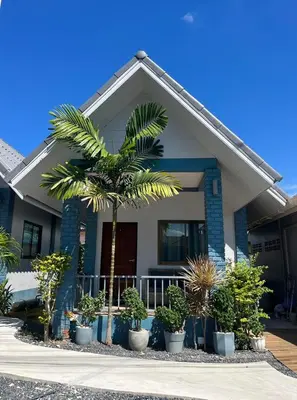 a palm tree in front of a house with plants at J&B House in Nai Yang Beach