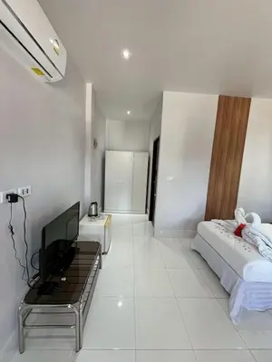 a white bedroom with a bed and a television at J&B House in Nai Yang Beach