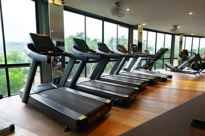 a row of treadmills in a gym with windows at Great 1BDR Kamala 500m to beach in Kamala Beach