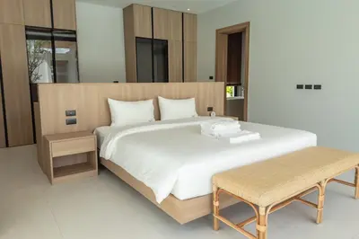 a bedroom with a large white bed and two benches at Mouana Breeze Maikhao 3-bedroom Pool Villa 9917 in Mai Khao Beach