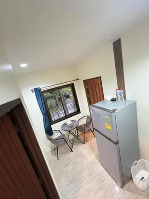 a kitchen with a refrigerator and a table and chairs at Fran Sim Da Guest House in Bang Tao Beach