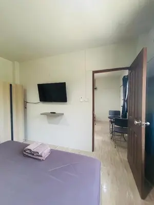 a room with a bed and a flat screen tv on the wall at Fran Sim Da Guest House in Bang Tao Beach