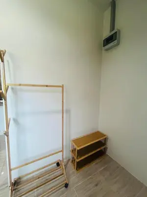 a room with a white wall and a wooden shelf at Fran Sim Da Guest House in Bang Tao Beach