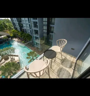 a balcony with two chairs and a table and a pool at City Gate Apartments Kamala Beach Phuket Thailand - LMY in Kamala Beach